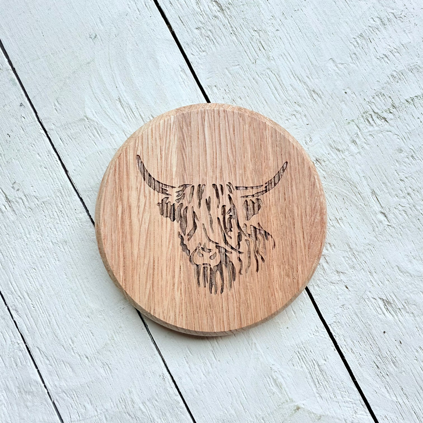 Barrel Oak Wooden coaster with a highland cow design on a light wooden 