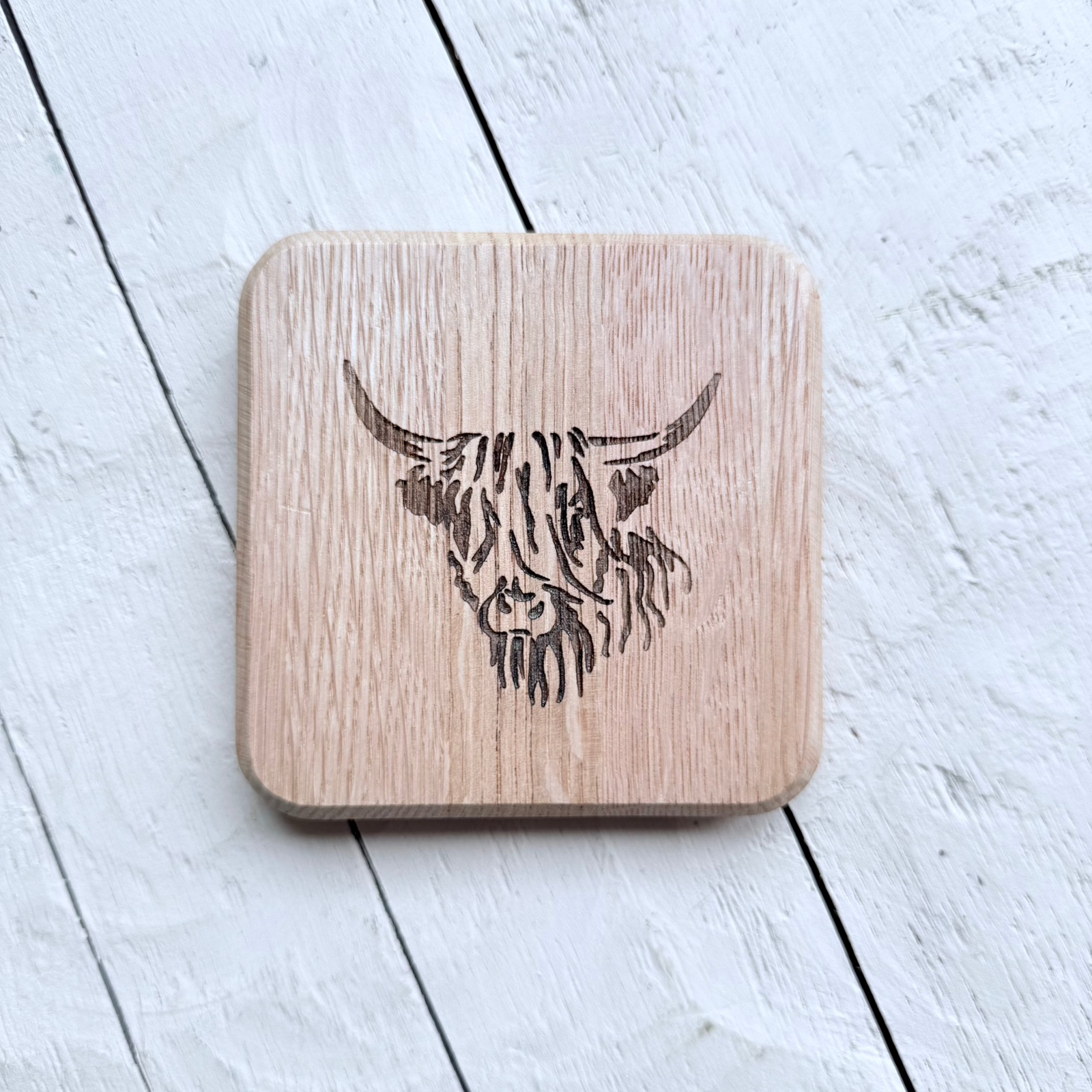 Barrel Oak Wooden coaster with engraved Edinburgh and coordinates on a light wooden surface