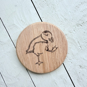 Barrel Oak Wooden circle coaster with a engraved puffin design on a light wooden surface