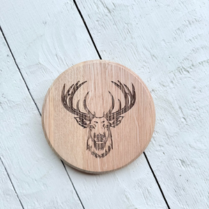 Wooden barrel oak circle coaster with stag design on a light wooden surface