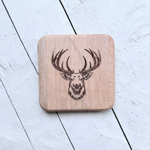 Wooden barrel oak coaster with stag design on a light wooden surface